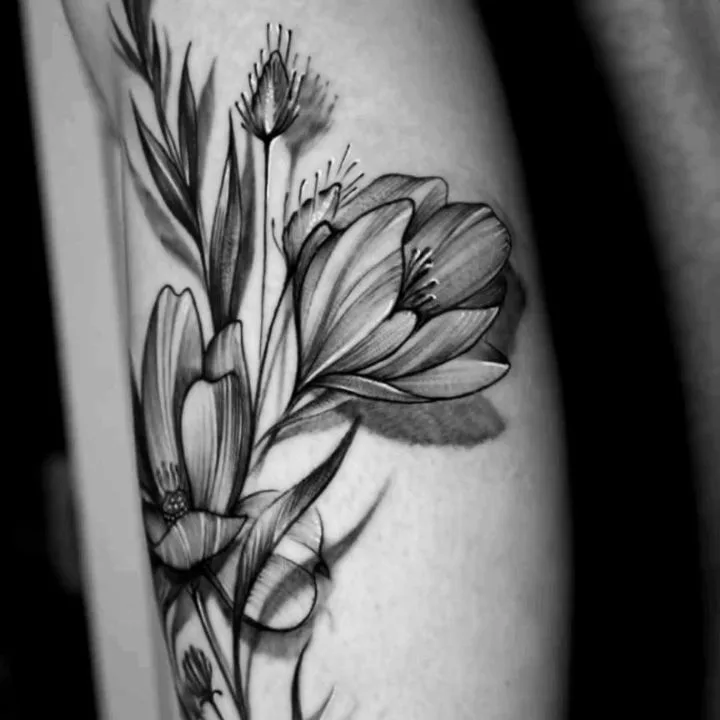 Tatuagem botânica no antebraço com flores, folhas e borboletas feita por Egle Justino