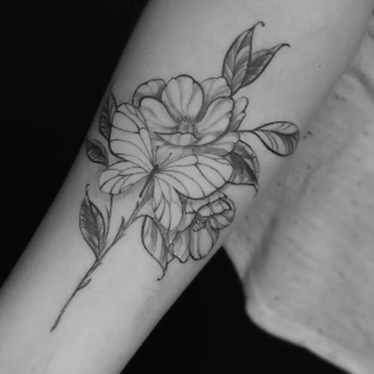 Tatuagem de composição floral em preto e cinza feita por Egle Justino