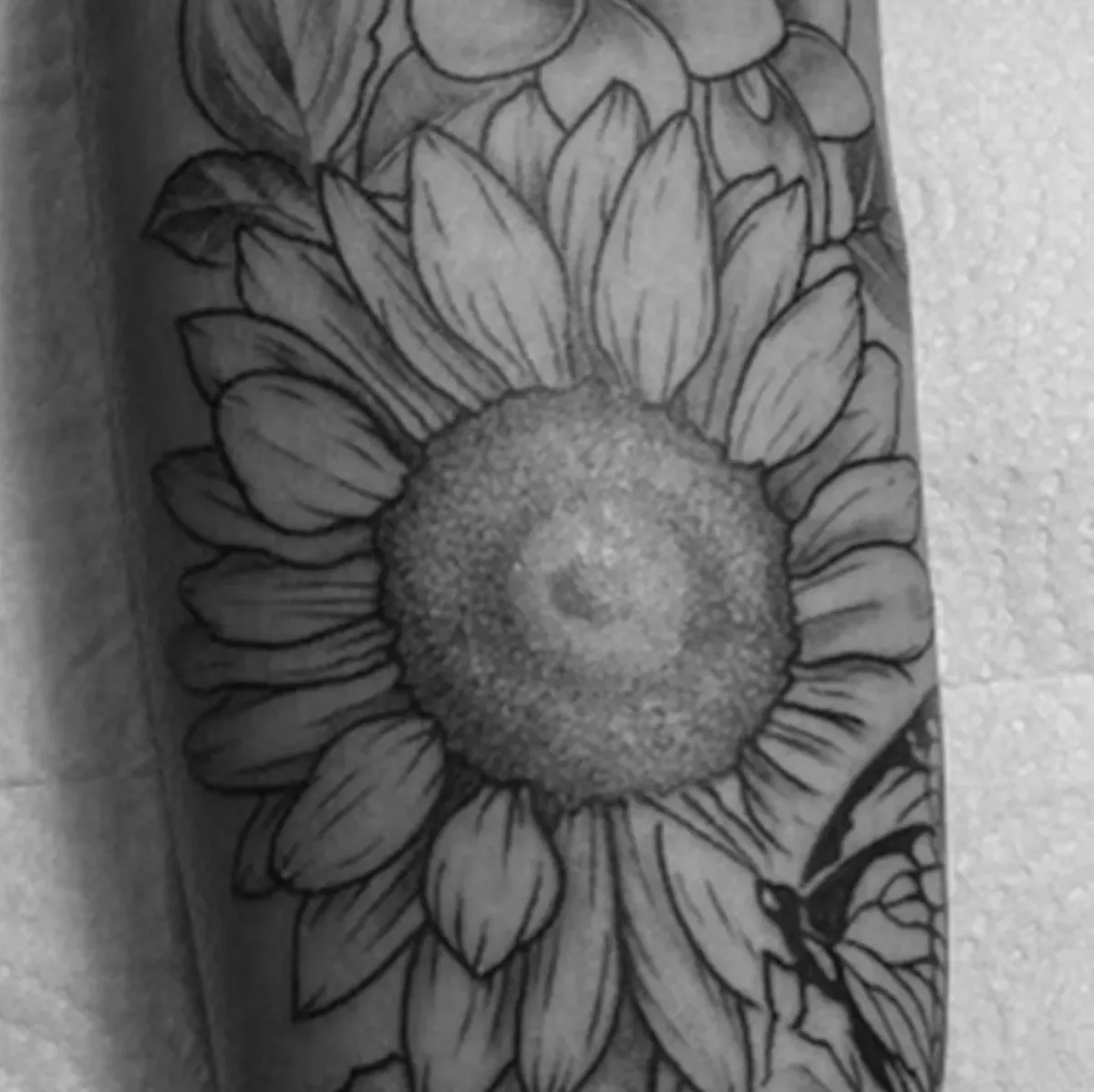 Tatuagem detalhada de girassol em preto e cinza feita por Egle Justino