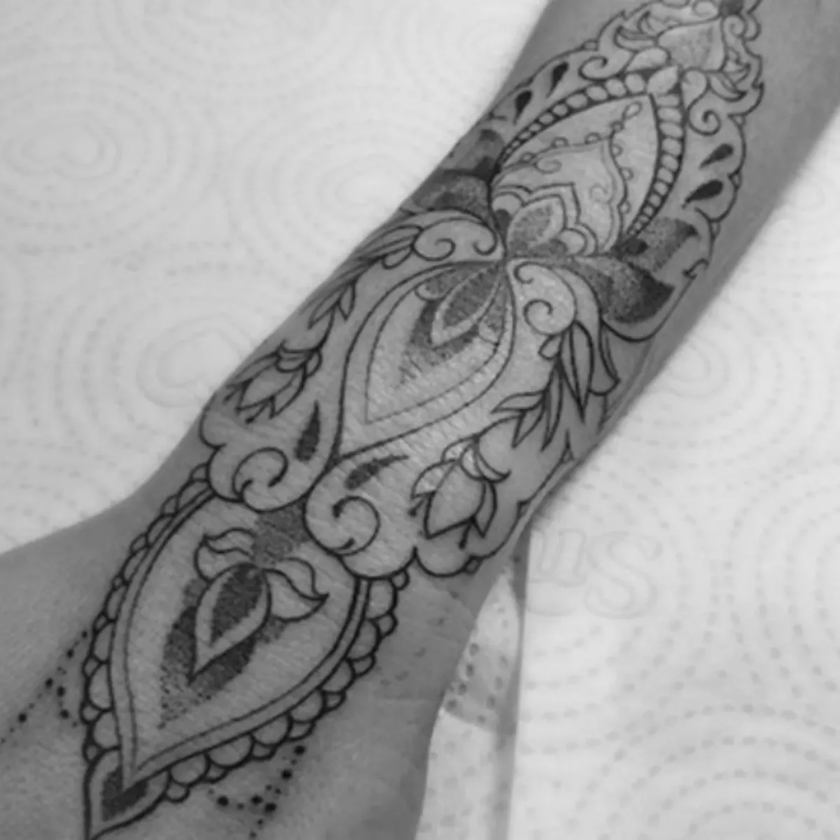 Tatuagem ornamental em preto e cinza no antebraço feita por Egle Justino