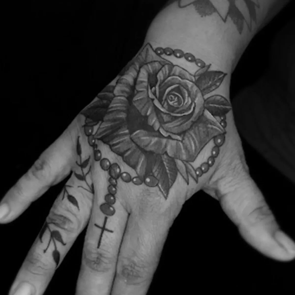 Tatuagem de rosa e rosário na mão feita por Egle Justino