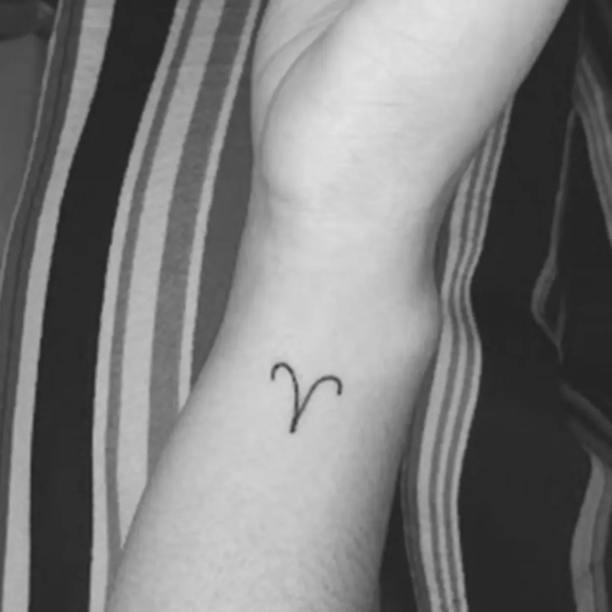 Tatuagem minimalista do símbolo de Áries feita por Egle Justino